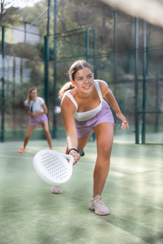 a woman playing padel tennis in an indoor court
